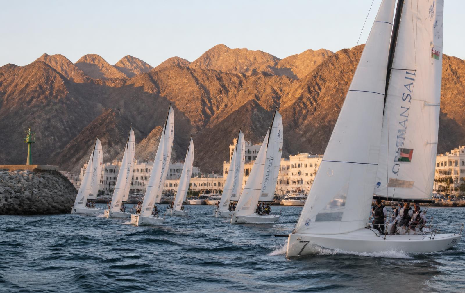 Racing fleet leaving an Omani marina at sunrise beneath the mountains